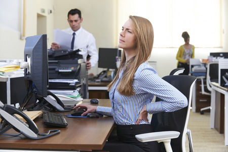 Businesswomen sitting at a desk in back pain